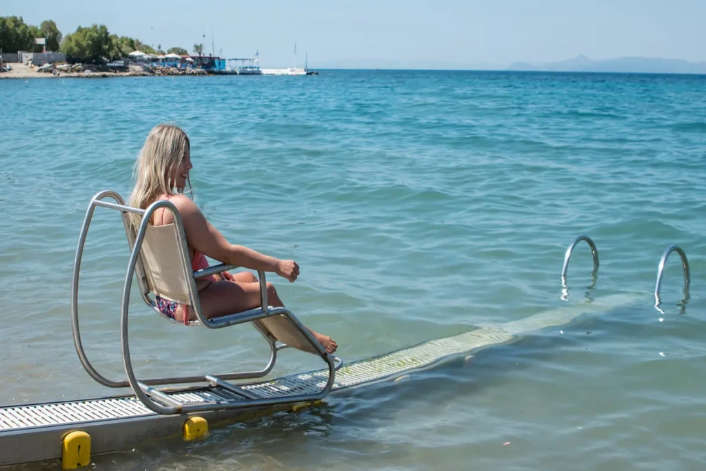 Woman uses Seatrac mobility aide to go down to the sea.